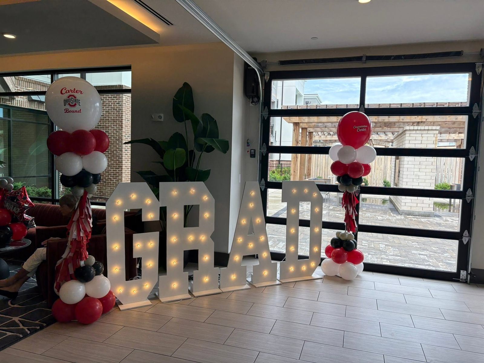 Lit GRAD marquee letters flanked by scarlet, black and white balloon columns and Ohio State foils. Graduation Celebrations by EPIC Parties in Middle Tennessee.