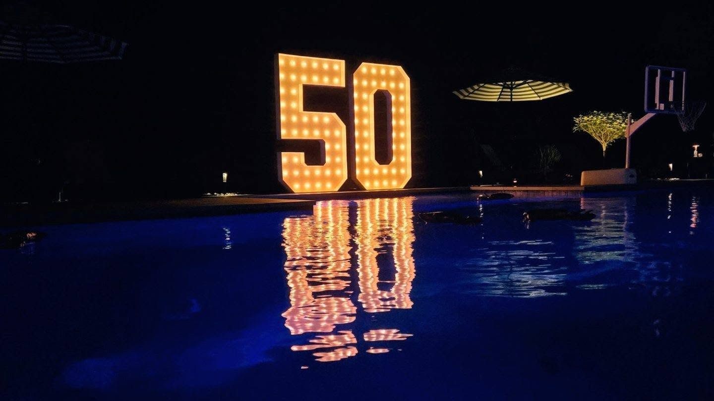 Illuminated marquee 50 numbers glowing over a pool at night for a birthday party. Private Parties by EPIC Parties in Middle Tennessee.